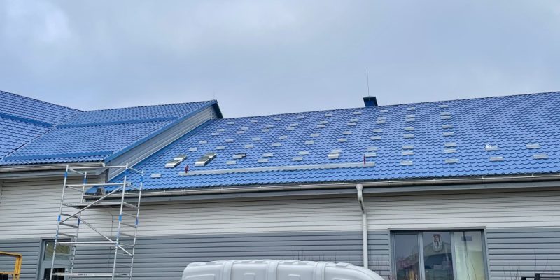 Ēka ar zilu jumtu, uz kura daļēji uzstādīti saules paneļi. Kuldīgas slimnīca